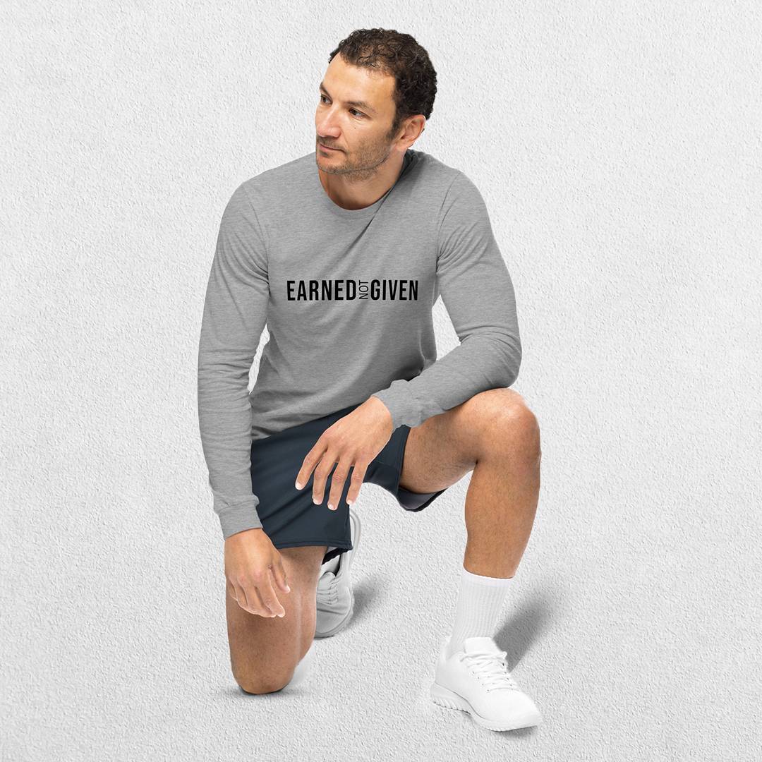 Model Wearing Athletic Heather GPW Earned Not Given Unisex Motivational Long Sleeve Tee in a studio background