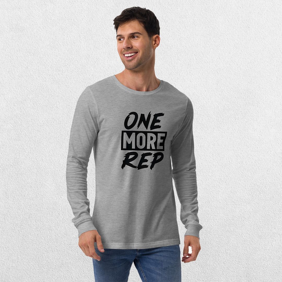 Model wearing the Athletic Heather GPW One More Rep Unisex Motivational Long Sleeve Tee with jeans in studio background.
