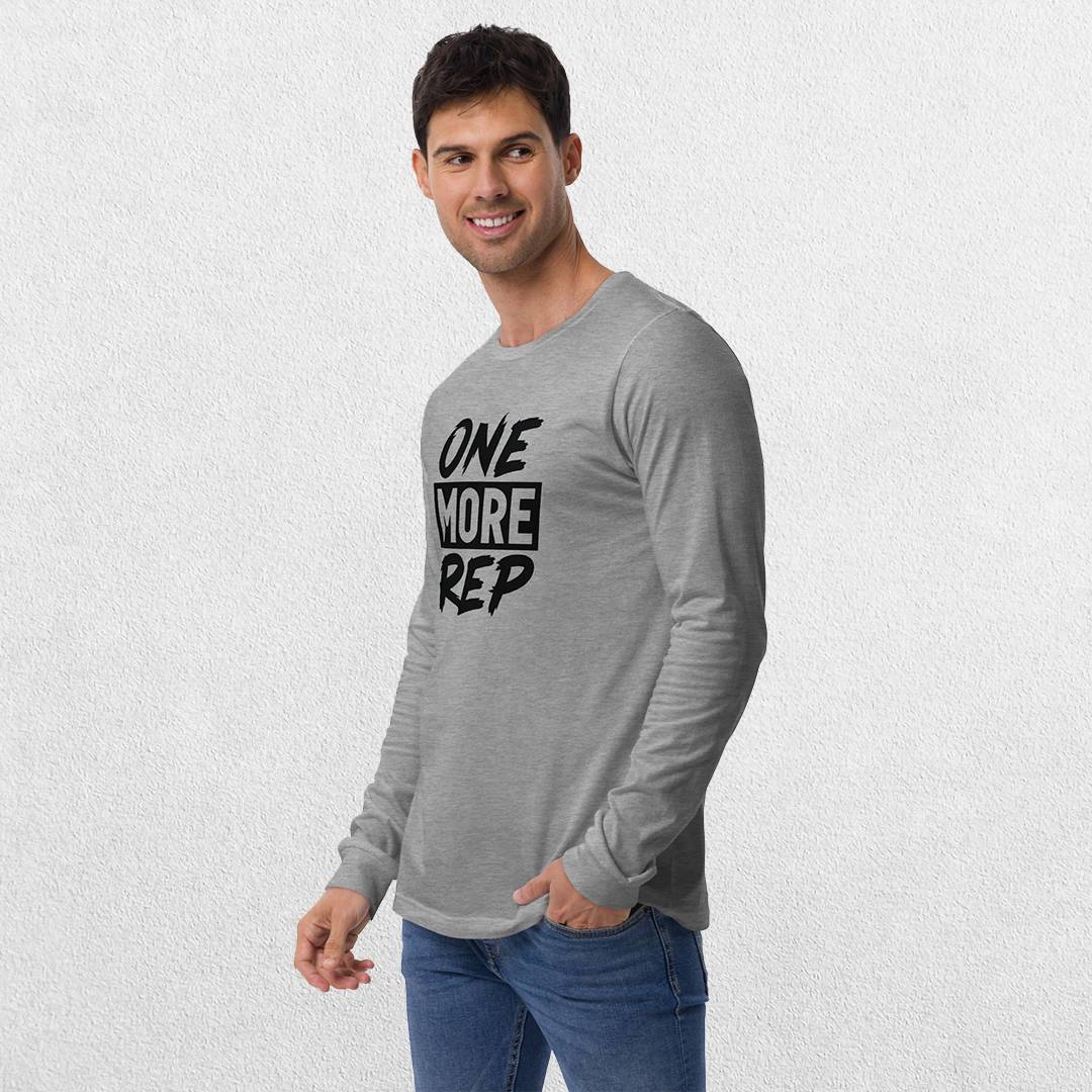 Model wearing the Athletic Heather GPW One More Rep Unisex Motivational Long Sleeve Tee with jeans in studio background.