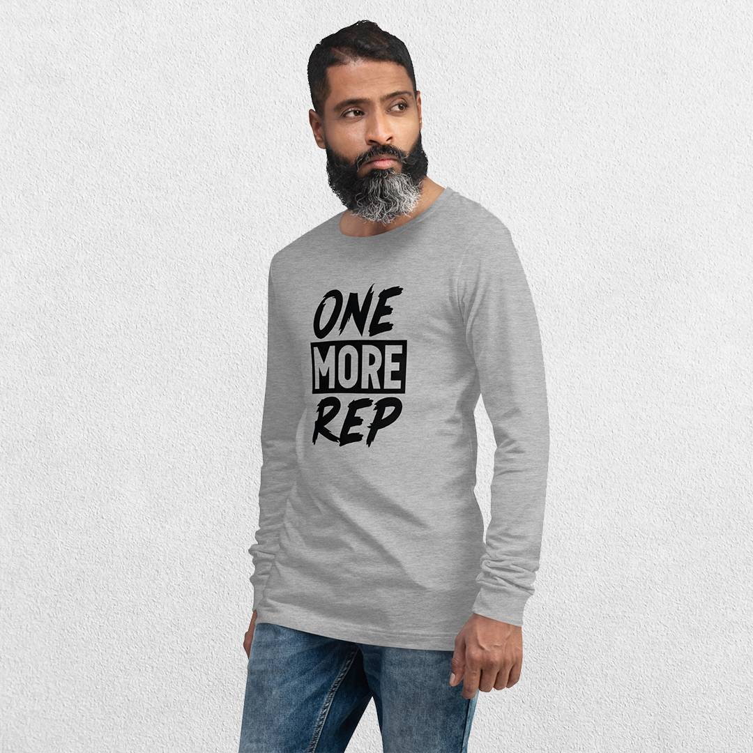 Model wearing the Athletic Heather GPW One More Rep Unisex Motivational Long Sleeve Tee with jeans in studio background.