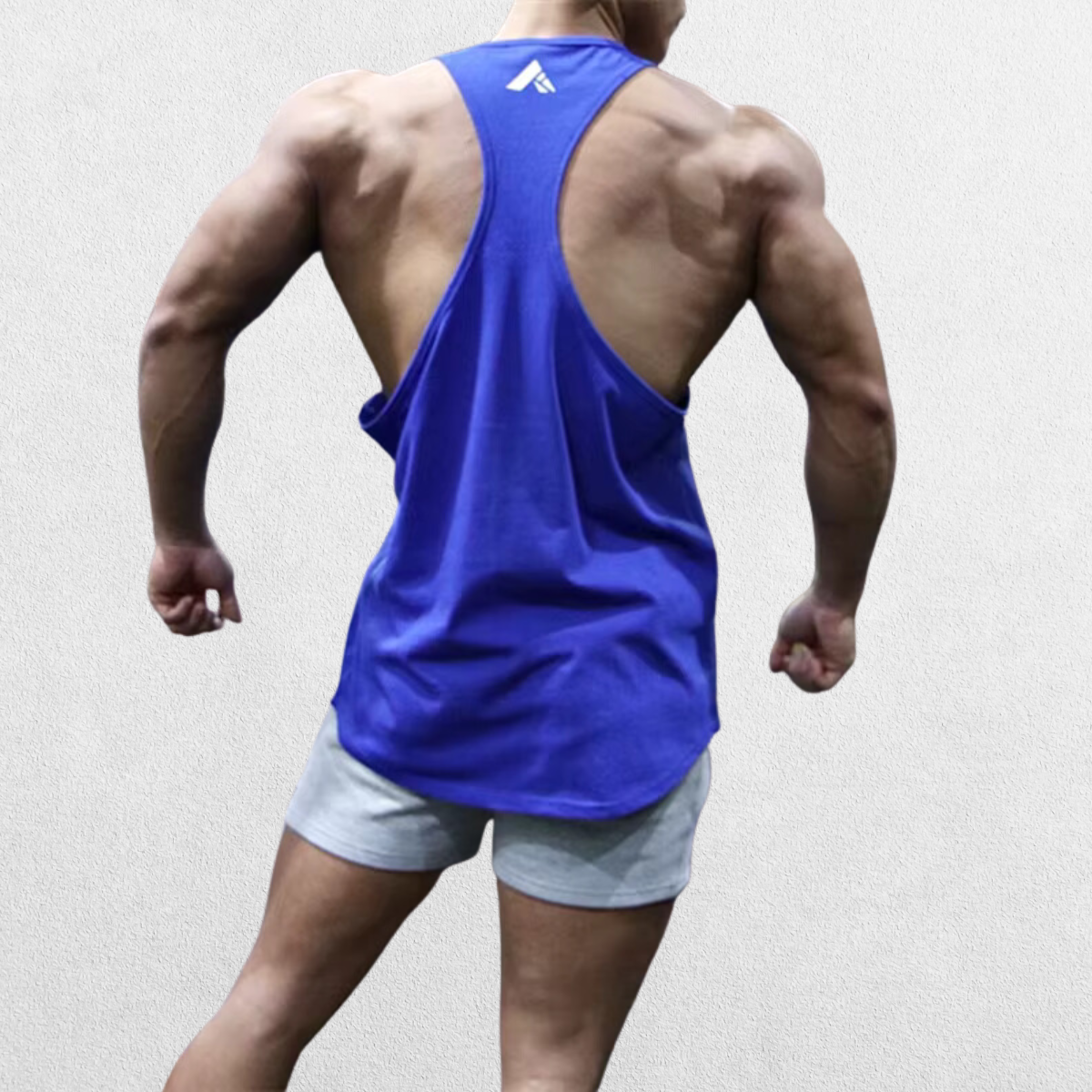 Back view of the GPW Athletic Gym Tank for Men in blue, featuring a stylish and supportive cut with a minimal studio backdrop.