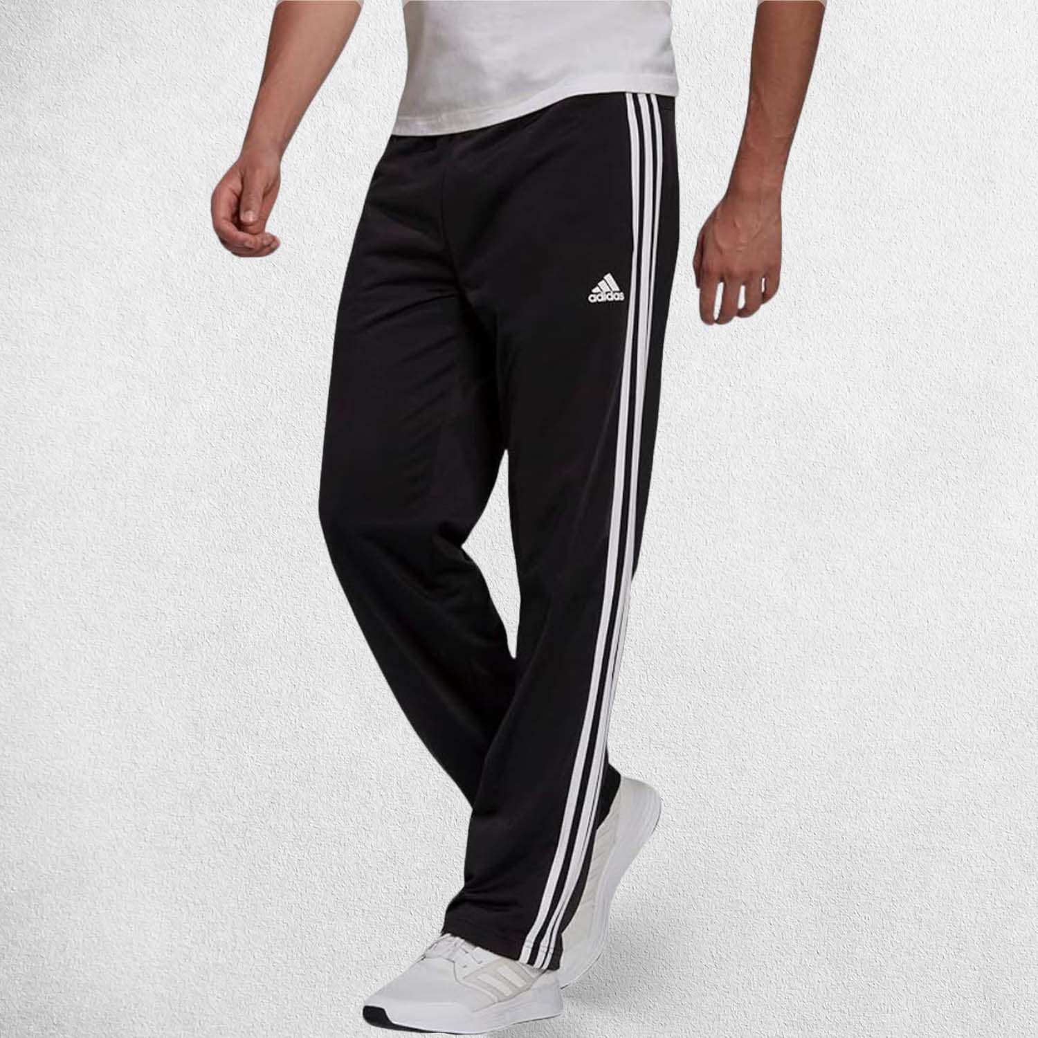Side Pose of Model Wearing Black 3-Stripes Tracksuit Pants made with Primegreen fabric