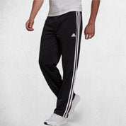Side Pose of Model Wearing Black 3-Stripes Tracksuit Pants made with Primegreen fabric