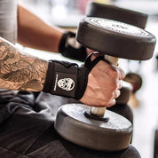 Weightlifter securing Black wrist wraps during a heavy powerlifting session