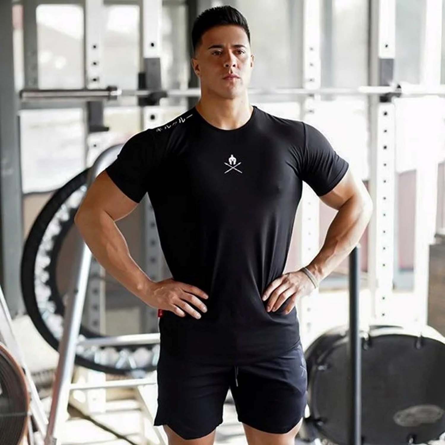 Model in a gym wearing black Black Men’s Letter Print Gym T-Shirt – Muscle Fit, Crew Neck, Cotton Workout Tee