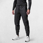 Fron tpose of Model Wearing Black Men's Quick-Dry Gym Track Pants highlighting breathable fabric.