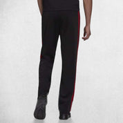 Back Pose of Model Wearing Black Scarlet 3-Stripes Tracksuit Pants made with Primegreen fabric