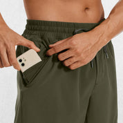 Close-up of Dark Olive Green GPW Men's Lightweight Quick-Dry Workout Shorts with Pockets in a studio background