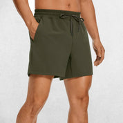 Front Close-up of Dark Olive Green GPW Men's Lightweight Quick-Dry Workout Shorts with Pockets in a studio background