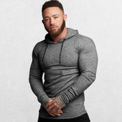 Model wearing a grey Hoodie in front of a grey studio background.