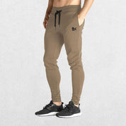 GPW Men’s Slim Fit Zip Athletic Pants Dark Beige Front View in Studio Background.