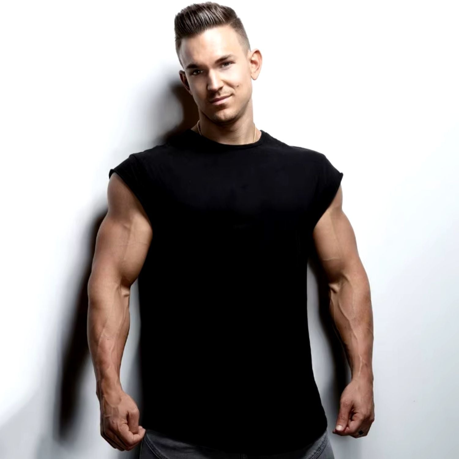 Man standing in a studio wearing a black men's quick-dry gym t-shirt, showcasing the tailored fit and sleek design