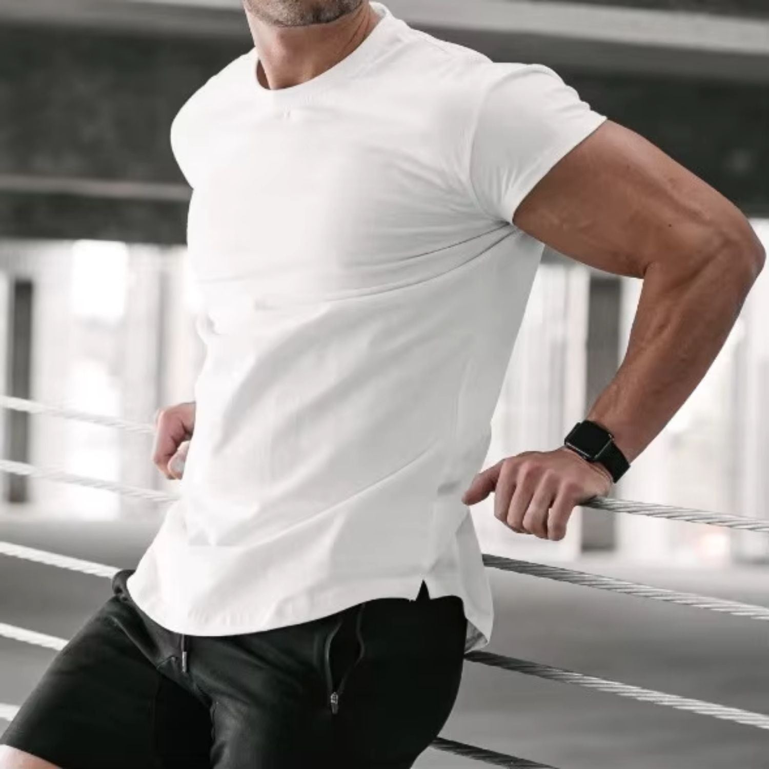 Model wearing a white quick-dry men's gym t-shirt, leaning into a stairs railing for a sleek and modern look.