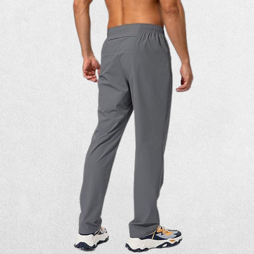 Back view of men's dark grey athletic trousers with a comfortable elastic waistband and functional zipper pockets.