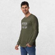 Model wearing the Military Green GPW Never Give Up Performance Long Sleeve Tee with jeans in a studio background.