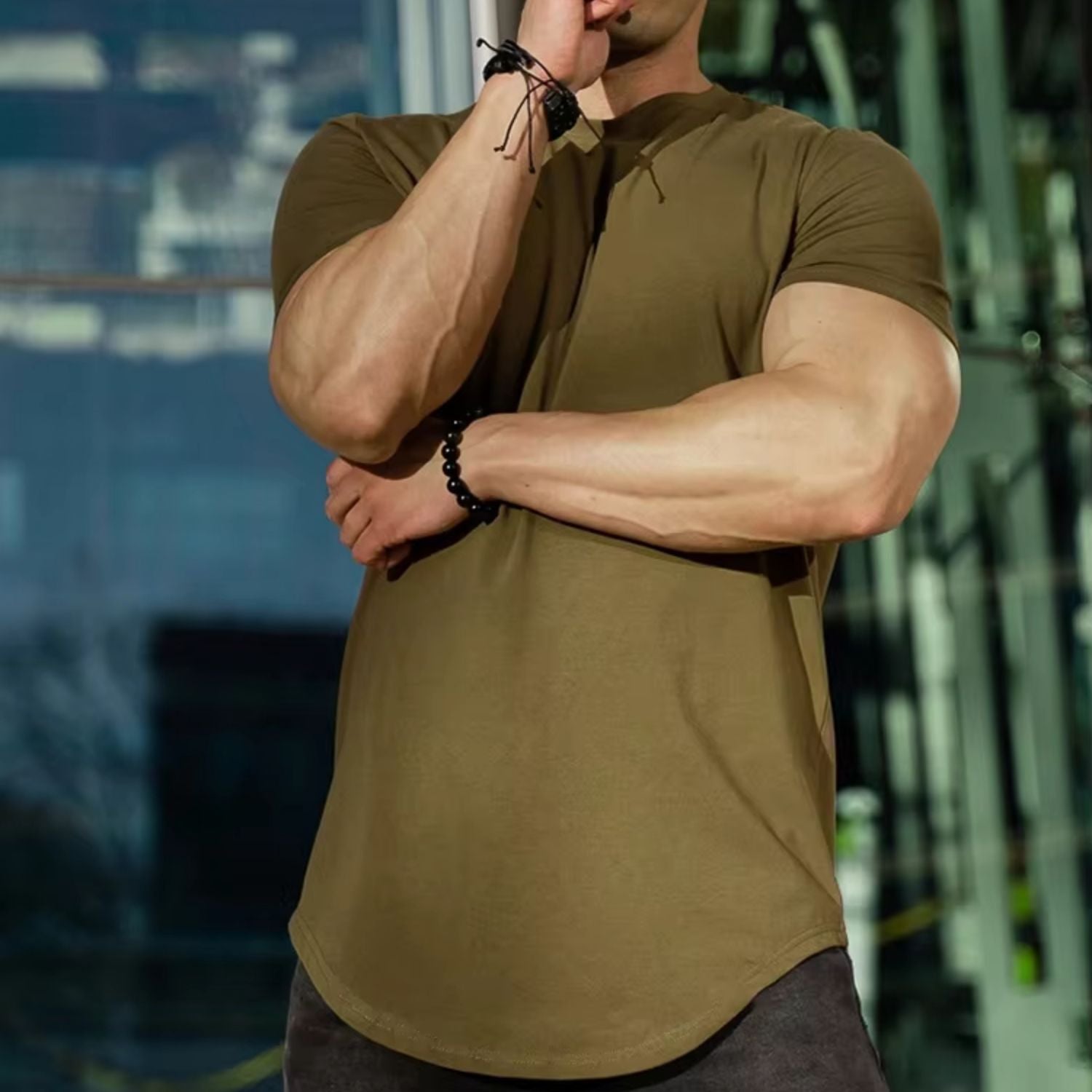 Model wearing an army green Muscle Fitness Summer T-Shirt in an outdoor gym setting.