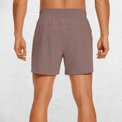 Back Close-up of Rosy Brown GPW Men's Lightweight Quick-Dry Workout Shorts with Pockets in a studio background