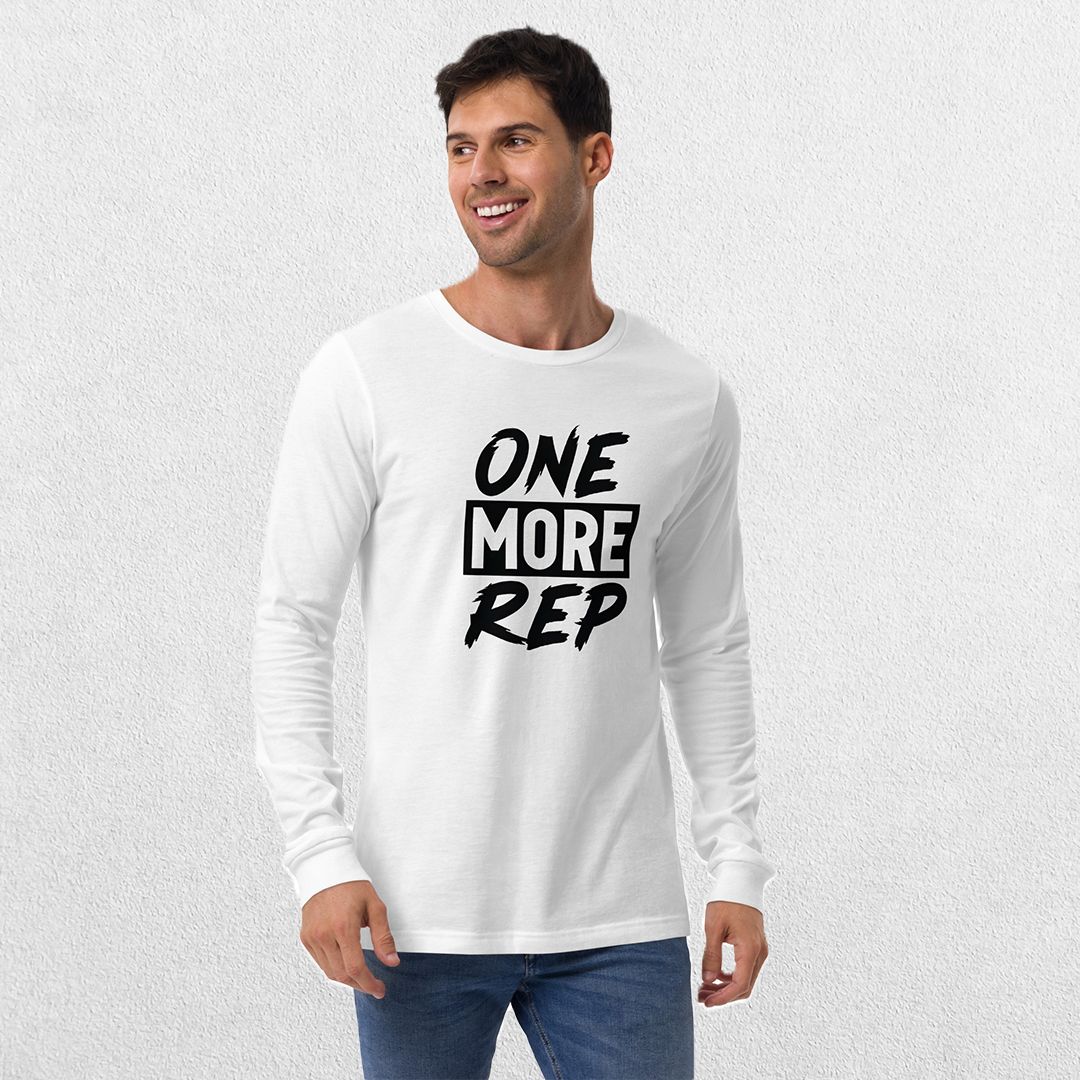 Model wearing the White GPW One More Rep Unisex Motivational Long Sleeve Tee with jeans in studio background.