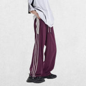 Model wearing Unisex Y2K Trousers in purple with a vintage baggy fit and elastic waistband, styled for a retro streetwear look, captured from a side profile.